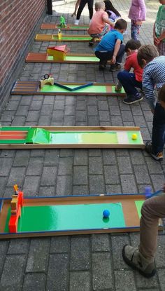 several children playing mini golf on the sidewalk