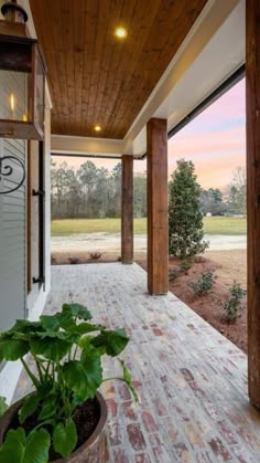 a porch with brick pavers and potted plant on the front lawn at dusk