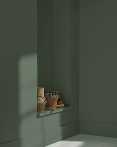 an empty room with green walls and pots on the window sill next to it