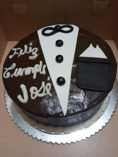 a chocolate cake with white frosting and black decorations on it's side in a cardboard box