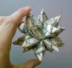 a person holding up a dollar origami flower