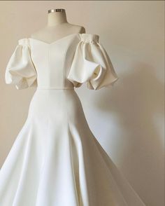 a white dress on a mannequin dummy with ruffle sleeves and an off the shoulder neckline