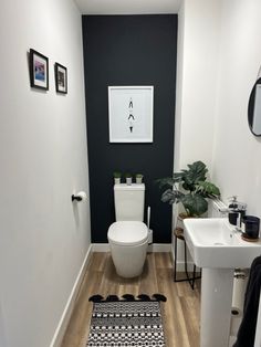 a white toilet sitting in a bathroom next to a sink and a bath room with a rug on the floor