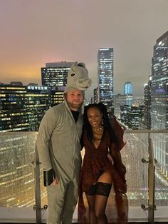 a man and woman posing for a photo in front of a cityscape