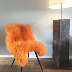 an orange chair sitting on top of a hard wood floor next to a wooden post