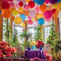 colorful paper lanterns hang from the ceiling above a table with flowers and plants in it