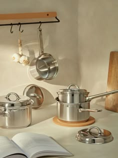 pots and pans are hanging on the wall next to an open book