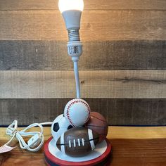 a lamp that is sitting on top of a wooden table next to a baseball and ball