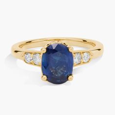 The rich warmth of the 14k yellow gold gorgeously contrasts and complements the deep blue oval-cut sapphire at the heart of this ring. A duo of accent diamonds lend luxurious sparkle on either side of the dramatic centre stone. Side Stone Ring, Blue Sapphire Wedding Ring, Dope Jewelry, Precious Gemstones, The Deep, Stone Ring, Oval Cut, Deep Blue, Stone Rings