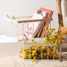 yellow flowers and books in a white wire basket next to a small birdcage