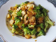 a white plate topped with broccoli and other food on top of a table