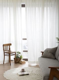 a living room with white curtains and wooden furniture