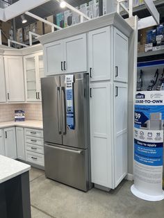 a kitchen with white cabinets and stainless steel appliances in the middle of an open floor plan