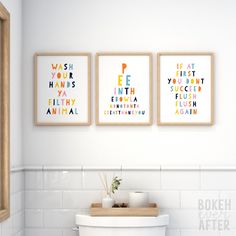 three framed art prints on the wall above a toilet in a bathroom with white tile