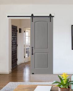 an open door leading to a living room with hardwood floors and white walls in the background