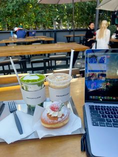 a laptop computer sitting on top of a wooden table next to a cup of coffee