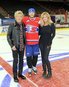 three people standing on an ice rink posing for a photo with one person wearing a hockey jersey