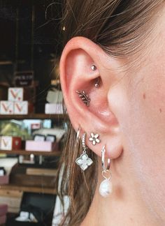 a close up of a person's ear with some piercings on it and other items in the background