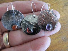 "Here are earrings made from sterling silver that I textured with a lace-like pattern. I made three pairs with 6mm stones. You have your choice of red garnet, orange carnelian, or purple amethyst.T he ear wire is handmade of sterling silver. The earrings are antiqued and hand polished to emphasize the texture. Disc measures 7/8\" (22 mm) Lightweight and easy to wear." Silver Round Carnelian Earrings, Silver Carnelian Earrings For Gift, Red Garnet, Ear Wire, Garnet, Sterling Silver Earrings, Silver Earrings, Dangle Drop Earrings, Amethyst