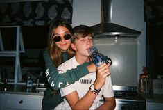 a boy and girl are drinking water in the kitchen