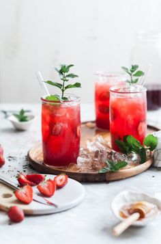 some strawberries are sitting on a table with drinks