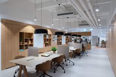 an empty office with desks and shelves on the wall, along with hanging lights