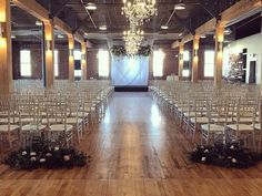 an empty room with rows of chairs and chandelier hanging from the ceiling, surrounded by wooden flooring