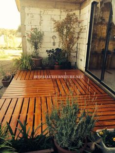 a wooden deck with potted plants on it and a sliding glass door to the outside