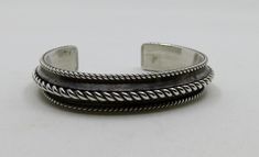 Solid, sterling silver bangle cuff, twisted wire overlay. Vintage Navajo, stunning piece by artisan Tom Hawk. Dimensions of bangle: Width 13mm (0.55") Length of metal 6" approx Internal dimensions 58mm x 45mm (2.5" x 1.85") Gap 1.1" (slightly adjustable)  Weight 43.6 grams Would suit a smaller 6 - 7" wrist Please check out my other designs and vintage pieces here: https://www.etsy.com/uk/shop/YouGotTheSilverUK  Click on customise for any custom queries or bespoke pieces. Artisan Silver Bangle Hand Wrapped, Artisan Hand-wrapped Silver Bangle, Artisan Silver Hand Wrapped Cuff Bracelet, Artisan Hand Wrapped Silver Cuff Bracelet, Artisan Hand-wrapped Silver Cuff Bracelet, Artisan Oxidized Finish Cuff Bangle Bracelet, Artisan Oxidized Bangle Cuff Bracelet, Sterling Silver Bangle, Twisted Wire