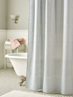 a white bath tub sitting next to a shower curtain in a bathroom with checkered flooring