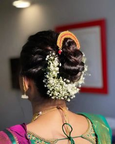 a woman with flowers in her hair wearing a green and pink sari blouse, looking off to the side