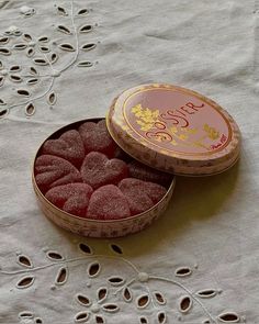 a small tin filled with raspberries sitting on top of a white table cloth