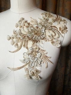 the back of a white dress with gold embroidered flowers on it's neckline