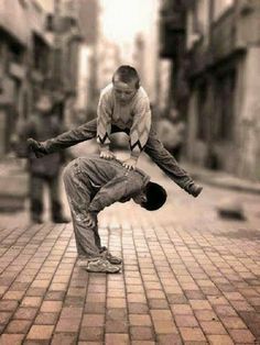 a man doing a handstand on a brick sidewalk in the middle of a city