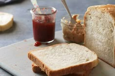 a loaf of bread sitting on top of a cutting board next to a jar of jam