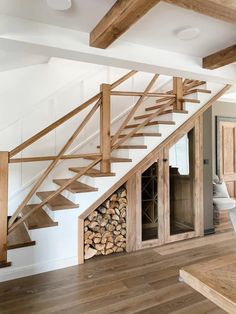 an open firewood storage unit under the stairs in a house with wood flooring