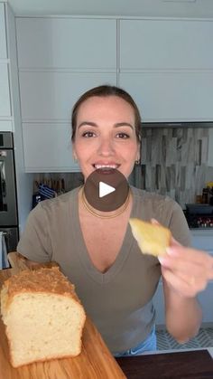 a woman holding a piece of bread on top of a wooden cutting board