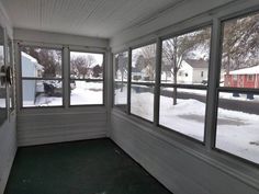 an empty screened porch with snow on the ground