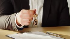 a person in a suit holding a key to a document and sitting at a table