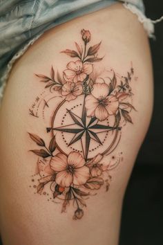 a woman's thigh with flowers and a compass tattoo on it