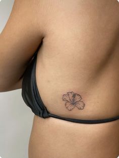 a woman's stomach with a small flower tattoo on her left side ribcage