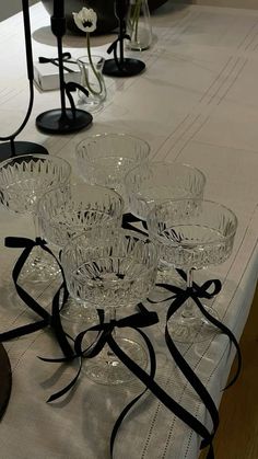 a table topped with lots of clear glasses on top of a white cloth covered table