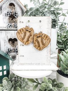 two heart shaped wooden earrings sitting on top of a table next to potted plants