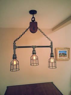 three light fixture hanging from the ceiling in a dining room with wood table and framed pictures