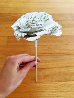 a person is holding a flower made out of book pages