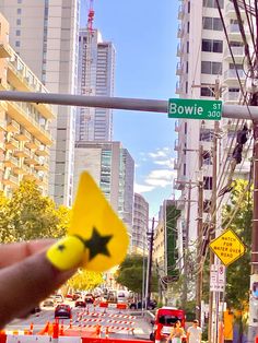 someone holding up a yellow star shaped object in front of a street sign that says bowie st