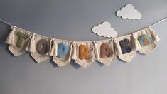 there are many different colors of yarn hanging from the line on the wall, with clouds in the background