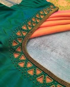 an orange and green sari with gold thread work on the border is laying next to some fabric