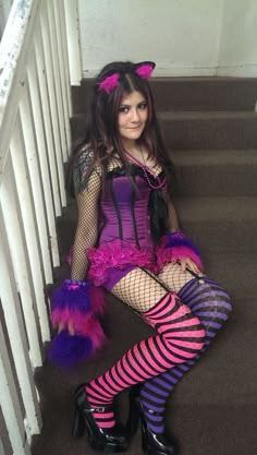 a woman sitting on the stairs wearing purple and black costume with cat ears, fishnet stockings, and tights