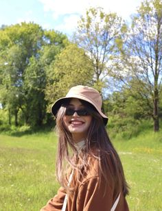 a woman in a hat and sunglasses is holding a frisbee on the grass